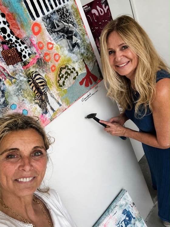 Gertrud Kemper und Sabine Schnorr hängen eine Arbeit auf